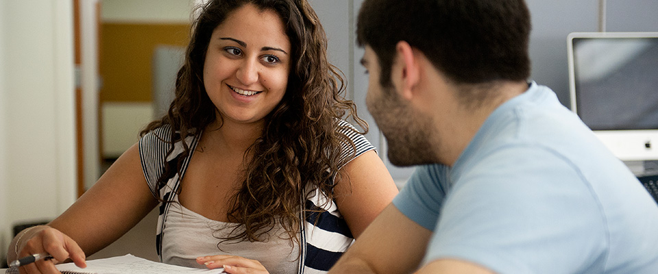 A writing tutor helps a student with her draft.